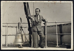 Merton Hodge standing next to a bell on board the Queen Mary