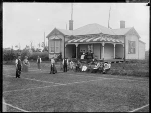 Group on a grass tennis court in front of a house, probably in Stratford