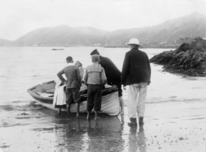 Group around a row boat at Pauls Beach, Karaka Bay, Wellington