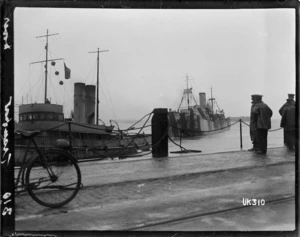 A tugboat towing a World War I troopship into berth, Dover