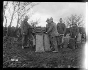 Soldiers operate a threshing and bagging machine, England