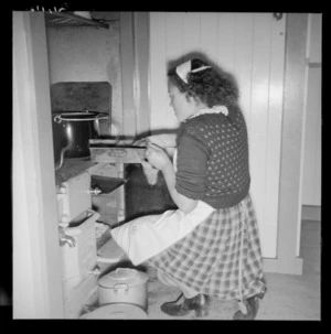 Young woman removing dish from oven, Te Kaha
