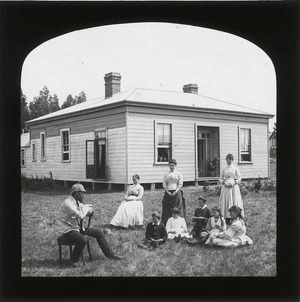 Man, women, and children, outside a house in Napier