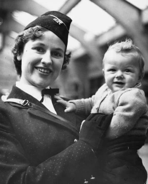 Railway hostess Miss Heather Gray holds seven-month old Michael Strickland while on duty at the Wellington Railway Station
