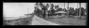View down a flat road running alongside a beach, in Samoa [probably near Apia]