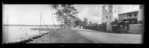 View in Samoa [probably near Apia], showing a straight road at the edge of a beach