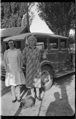 Nell and Helen Hare standing beside their Auburn car with Nellie the dog