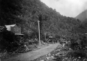 Scene at the foot of the Otira Gorge including the Otira Hotel, a small crowd of people and two horse drawn carriages