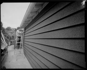 Man working on pebble board house exterior