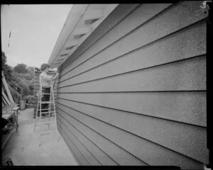 Man working on pebble board house exterior