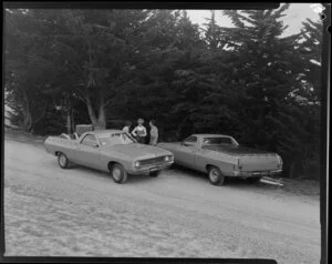 People talking next to two Ford Falcon utes