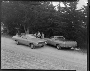 People talking next to two Ford Falcon utes