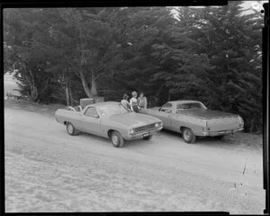 People talking next to two Ford Falcon utes