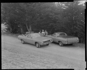 People talking next to two Ford Falcon utes