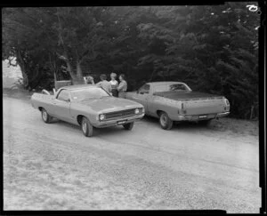 People talking next to two Ford Falcon utes