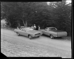 People talking next to two Ford Falcon utes