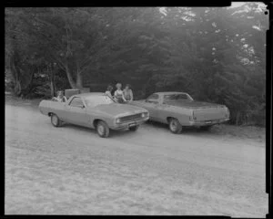 People talking next to two Ford Falcon utes