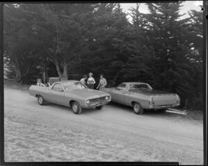 People talking next to two Ford Falcon utes