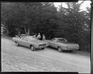 People talking next to two Ford Falcon utes