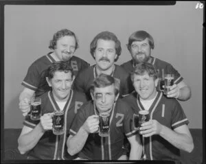 People (including one with fake black eye) in softball uniforms drinking Lion beer in studio