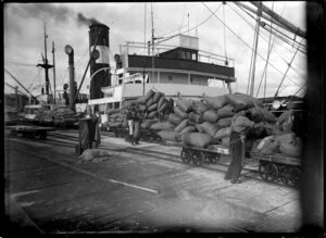 Chelsea sugar works, Birkenhead, Auckland, showing sacks of sugar on railway wagons next to ship at wharf