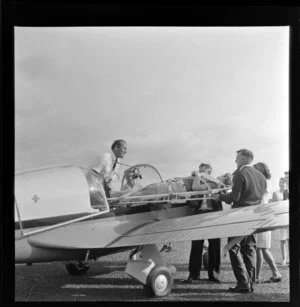 Patient on stretcher being removed from the aeroplane Fletcher FU24 ZK-COA, Royal New Zealand Aero Club pageant, Ardmore