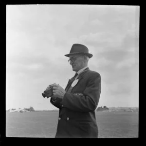 Unidentified man using a camera at the Royal New Zealand Aero Club pageant, Ardmore