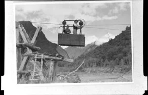 Two men in a cable tram crossing Jacobs River, Fox Glacier, West Coast Region