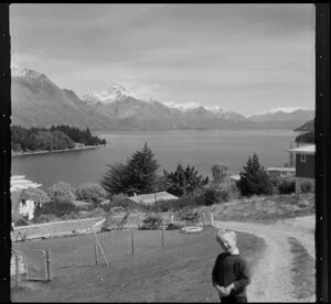 Unidentified boy in a suburban backyard with Lake Wakatipu and Walter Peak in the distance, Queenstown