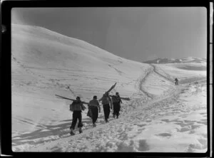 Skiers walking up Coronet Peak