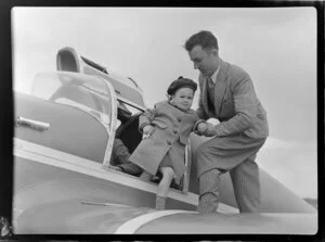 Andrea Mercer being helped out of the aeroplane by pilot Mr D O'Donnell after a trip 'for whooping cough', Canterbury Aero Club