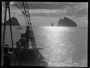 A man standing at the bow of a boat in the early morning or evening