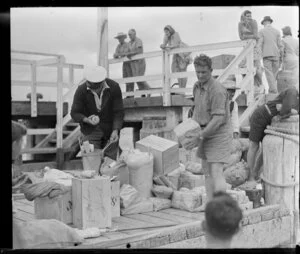 Two men sorting parcels on the wharf, cream launch trip, Bay of Islands