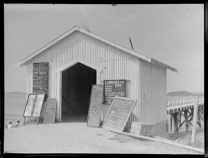 A shed at the wharf, with boards advertising the various boat rides available, Paihia