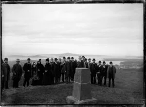 Group of people standing by stone obelisk on summit of Maungawhau-Mount Eden, Auckland
