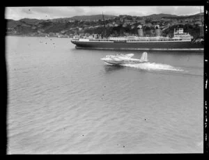 Flying boat, Centaurus, taxiing past an unidentified ship, Wellington Harbour