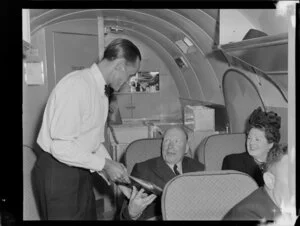 Airline steward F Bennett giving reading material to a passenger in a Dakota aircraft