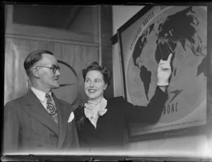 Mary Wootton (Miss New Zealand) with Mr Kilpatrick at the Whites Aviation offices, Auckland, with BOAC (British Overseas Airways Corporation) poster