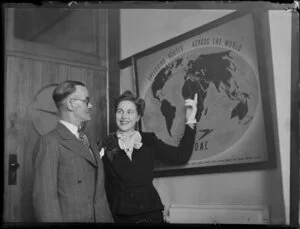 Mary Wootton (Miss New Zealand) with Mr Kilpatrick in Whites Aviation office, Auckland, with BOAC (British Overseas Airways Corporation) poster