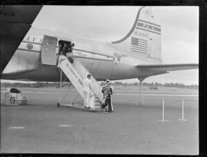 Disembarking from Pan American World Airways aeroplane Clipper Red Jacket; includes a steward helping a child down the gangway