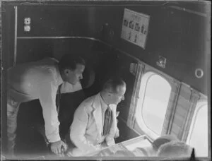 Two men look out of the window of the seaplane Aotearoa in Suva