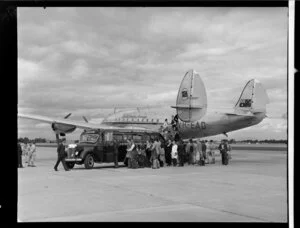 Passengers climbing on to a Newmans bus in front of Constellation aircraft