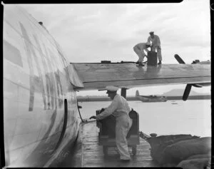 Staff of TEAL (Tasman Empire Airways Limited), loading baggage onto the airplane 'RMA Auckland', in Auckland harbour