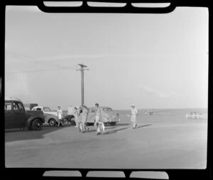 Passengers and crew with fish catch approaching Qantas transport vehicles, Flying Boat Base, Darwin