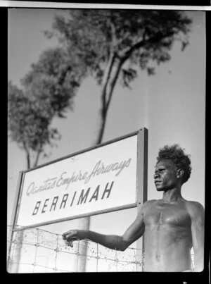 Aboriginal man standing next to a Qantas Empire Airways sign, Berrimah, Darwin, Australia