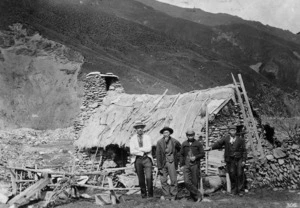 Chinese miners with George McNeur outside a stone dwelling, Macetown