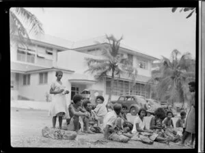 Group of unidentified locals sitting opposite a building and talking to each other, Port Moresby, Papua New Guinea