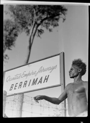 Aboriginal man standing next to a Qantas Empire Airways sign, Berrimah, Darwin, Australia