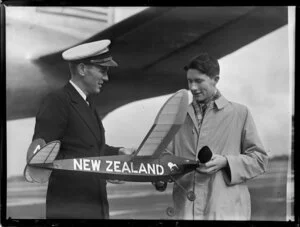 Unidentified people infront of Pan American World Airways holding Wakefield trophy model aeroplane prior to their departure at Whenuapai airport