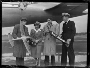 Unidentified people infront of Pan American World Airways holding Wakefield trophy model aeroplane prior to their departure from Whenuapai airport